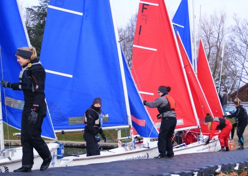 Ladies team racing helms & crews climbing into red or blue Fireflys with matching sails - nice !
