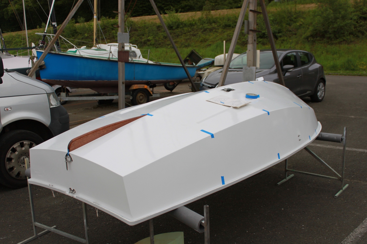 A GRP Mirror dinghy hull upside down on stands being measured with blue masking tape marking the hull stations