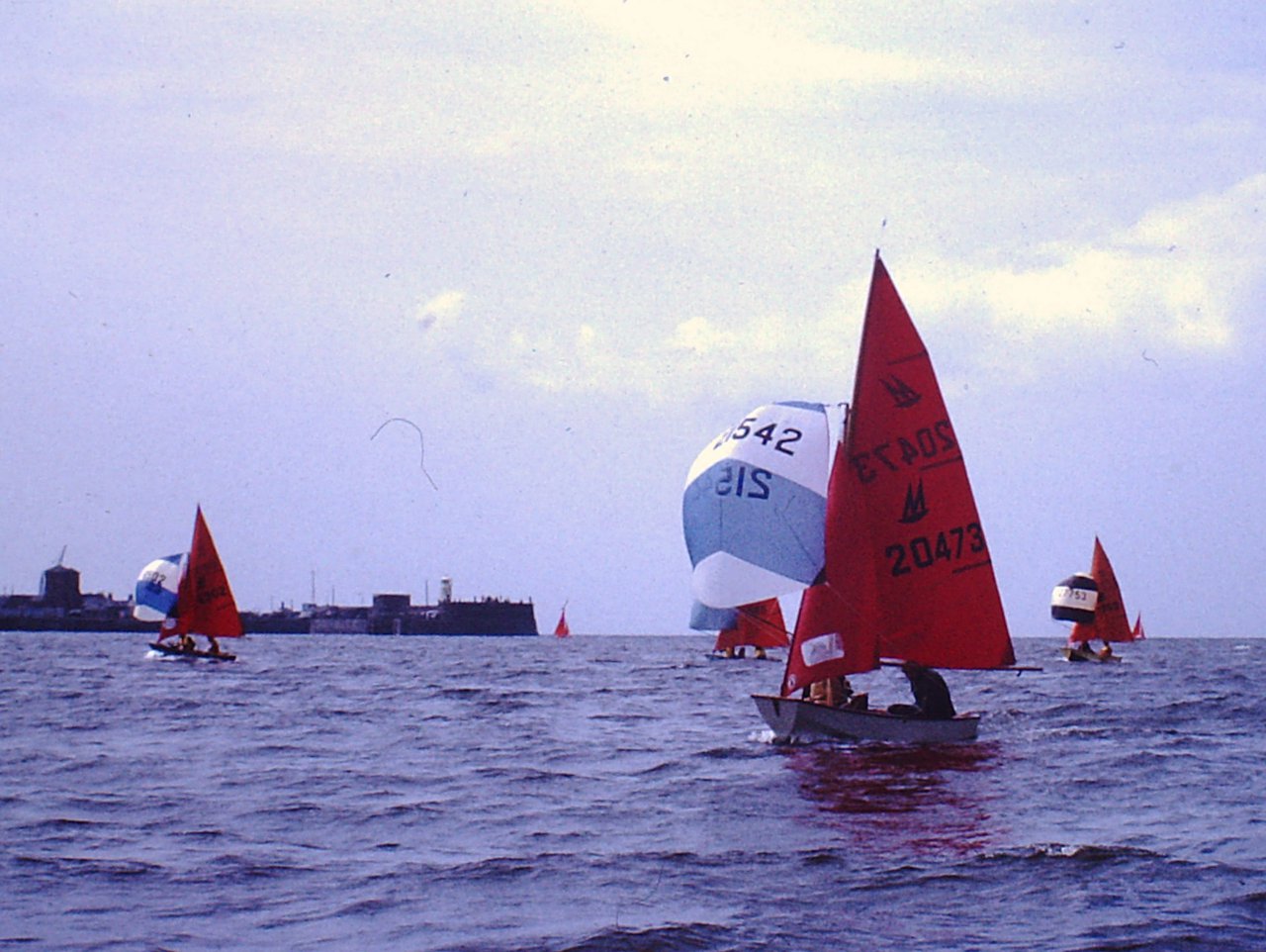 A fleet of Mirror dinghies running down to finish a race