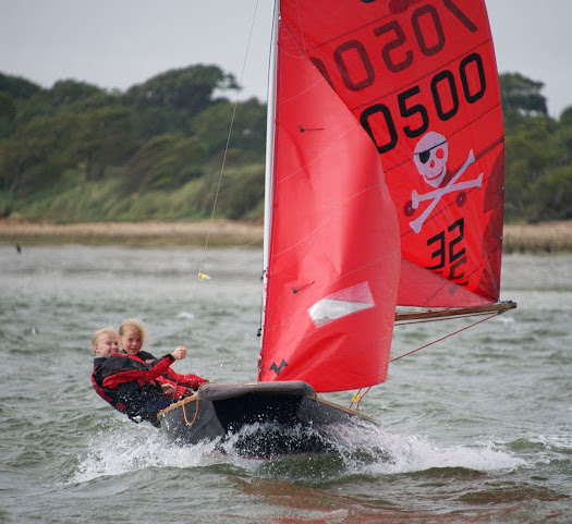 Mirror dinghy with skull and cross bones on mainsail on a windy day