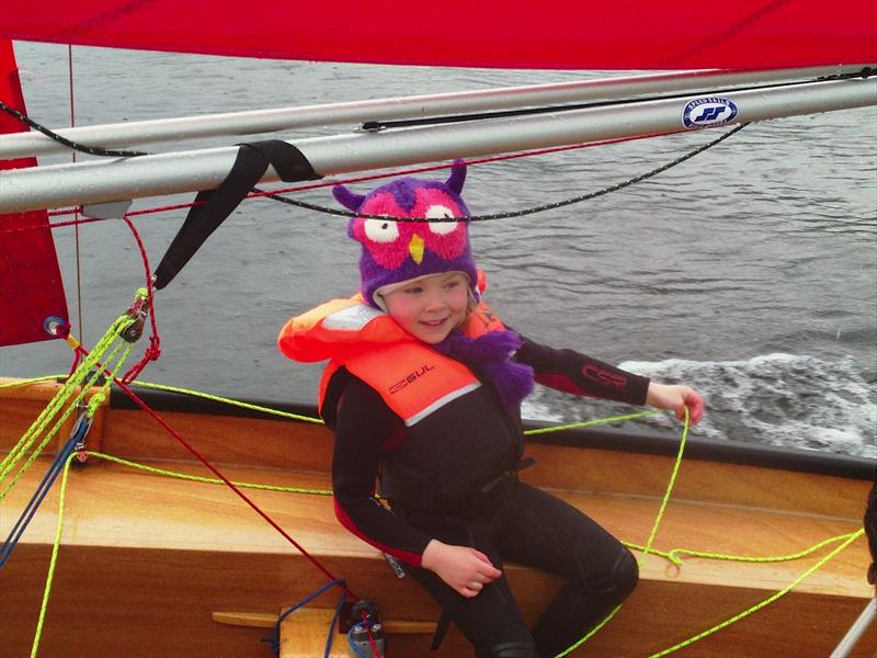 A young girl crewing a Miirror dinghy with lifejacket and owl hat