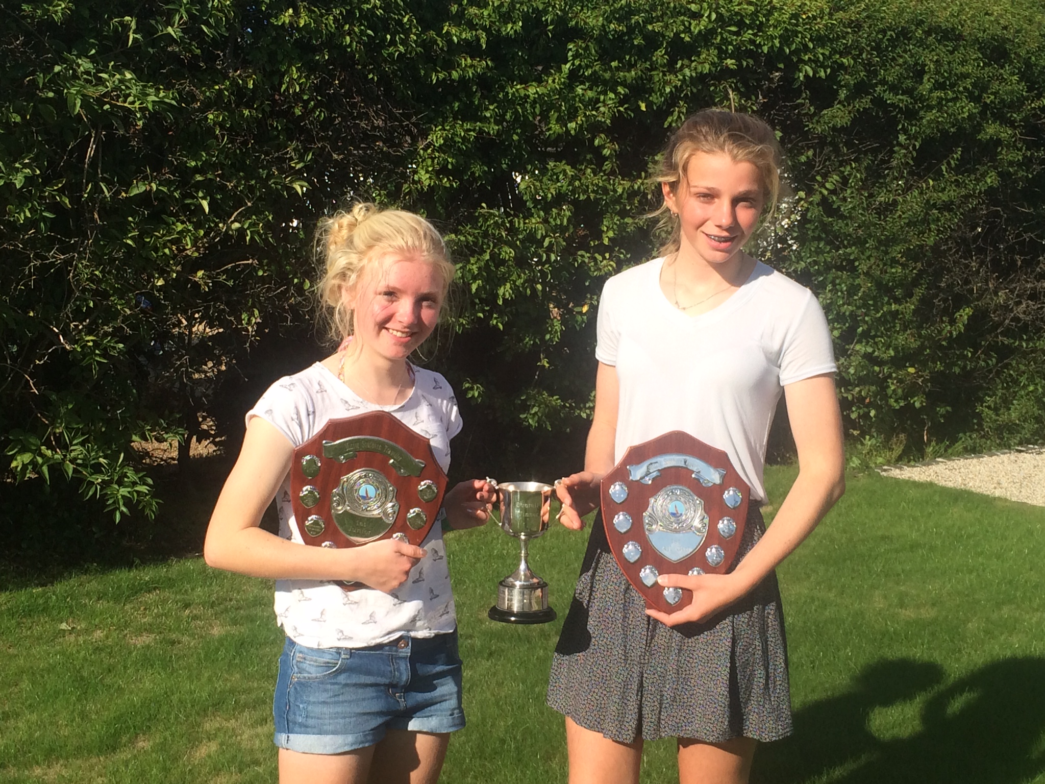 Two girls holding their trophies - a cup and two shields