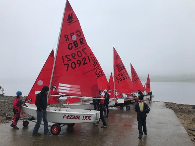Mirror dinghies launching from a slipway in misty weather