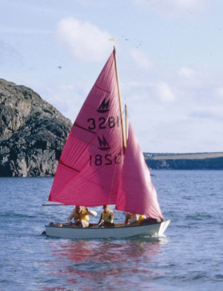 A white Mirror dinghy being sailed by a family