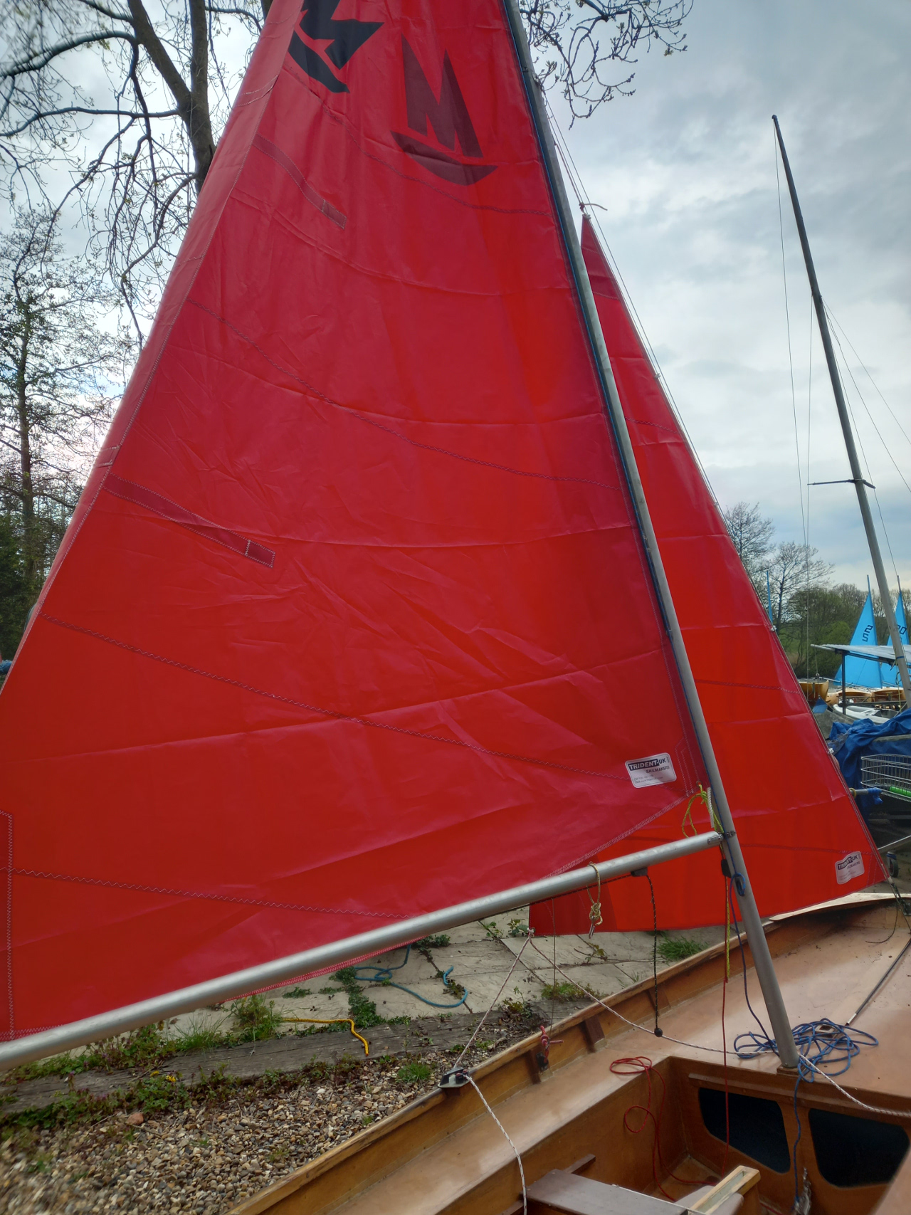 A wooden Mirror dinghy with Bermuda rig and sails with no numbers
