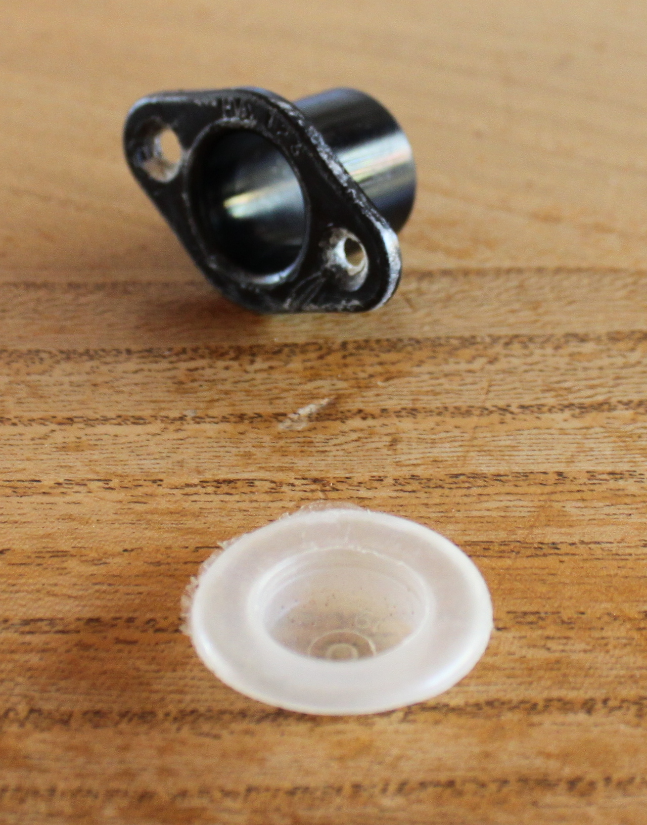 A black plastic drainage hole fitting and a semi-transparent plastic cap to seal it