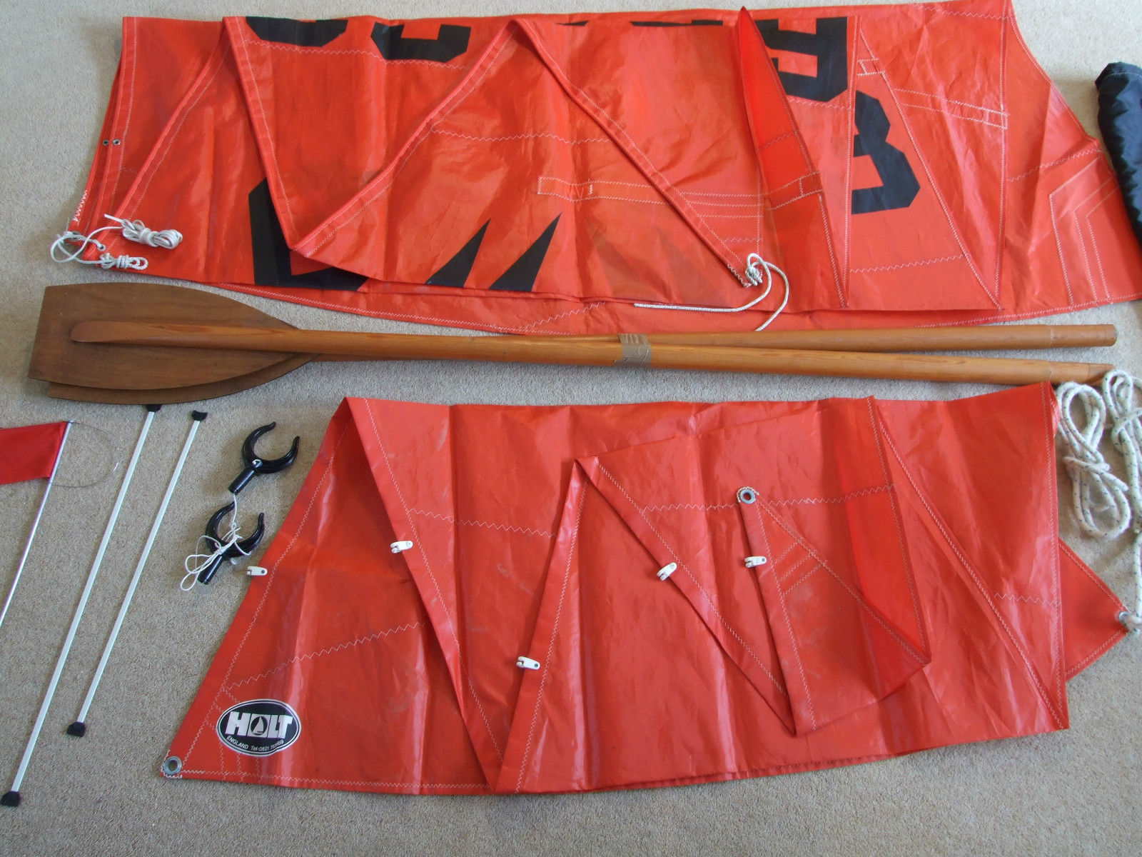 A pair of Mirror oars plus some rowlocks, folded sails, sail battens and a burgee laid out on a carpet