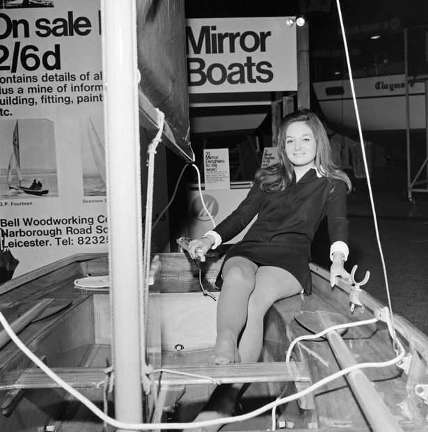 A Mirror dinghy with a female model sitting in it, veiwed from the aft quarter