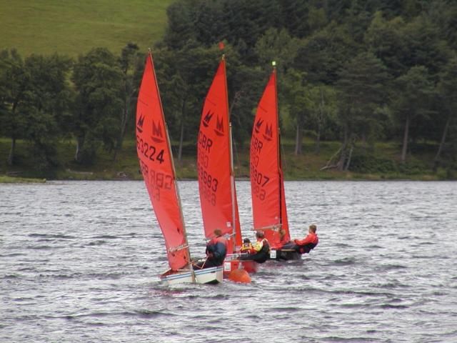 Three Mirror dinghies racing away from the leeward mark and away from the camera