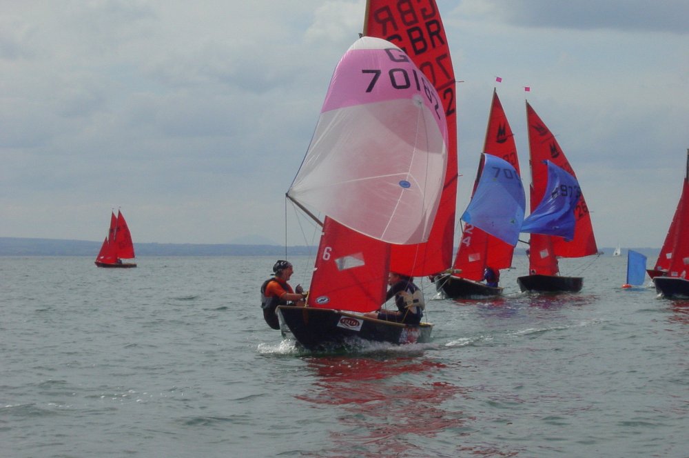 A blue Mirror dinghy racing on a reach with spinnaker set