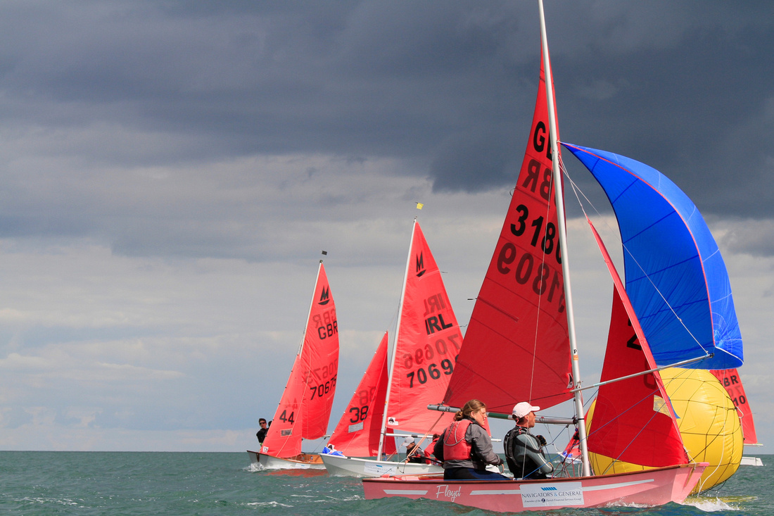 A pink Mirror dinghy flying a blue spinnaker