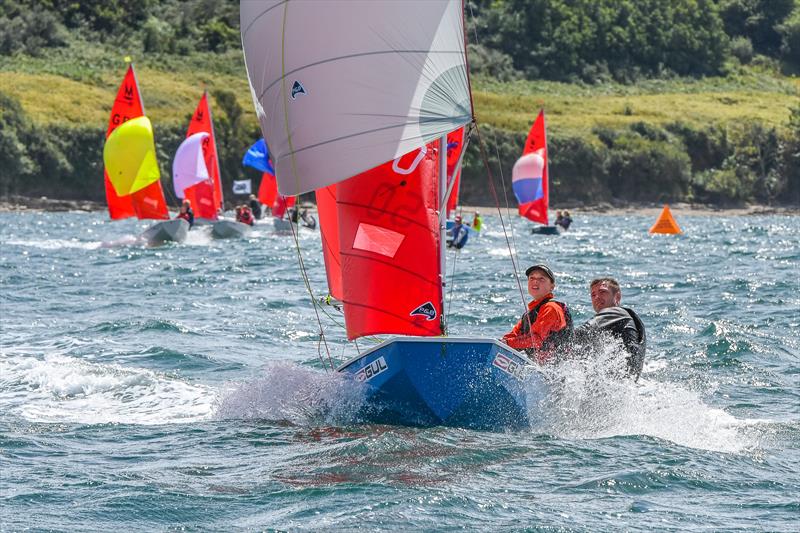 A blue GRP Mirror dinghy racing with spinnaker towards the camera sailed by a father and daughter