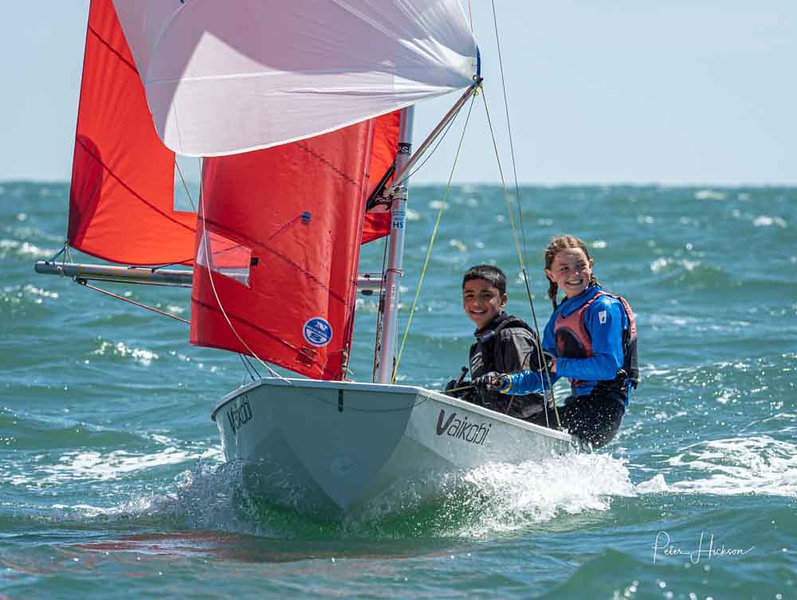 A white Winder Boats GRP Mirror dinghy with young helm & crew sailing towards the camera
