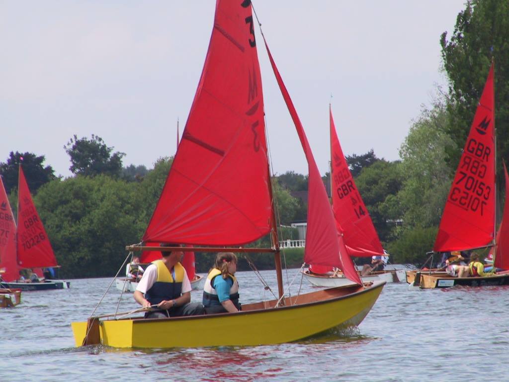 A fleet of Mirror dinghies, including Mirror number three, racing to windward on a small lake