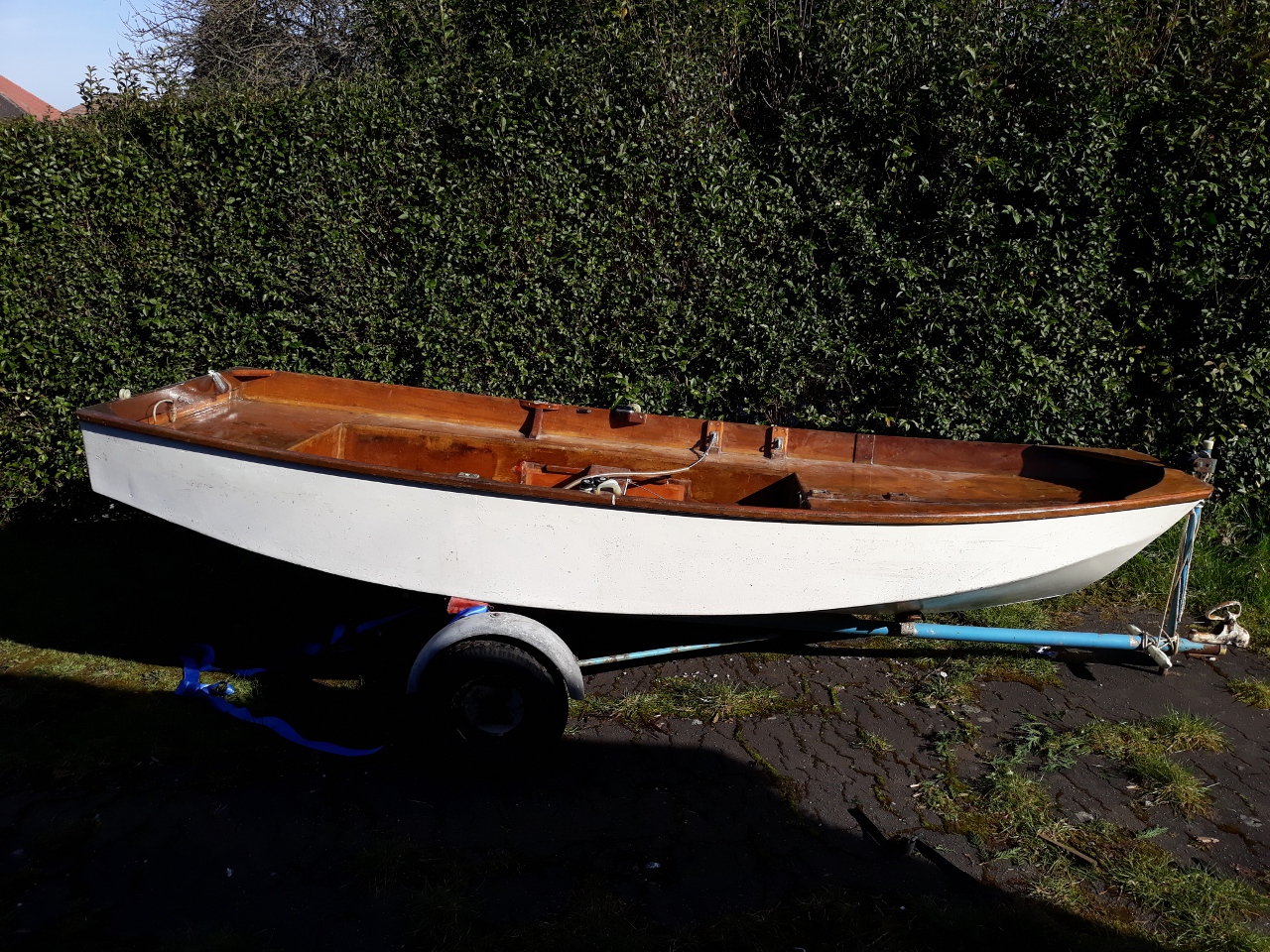 A white wooden Mark 1 interior Mirror dinghy unrigged on a drive