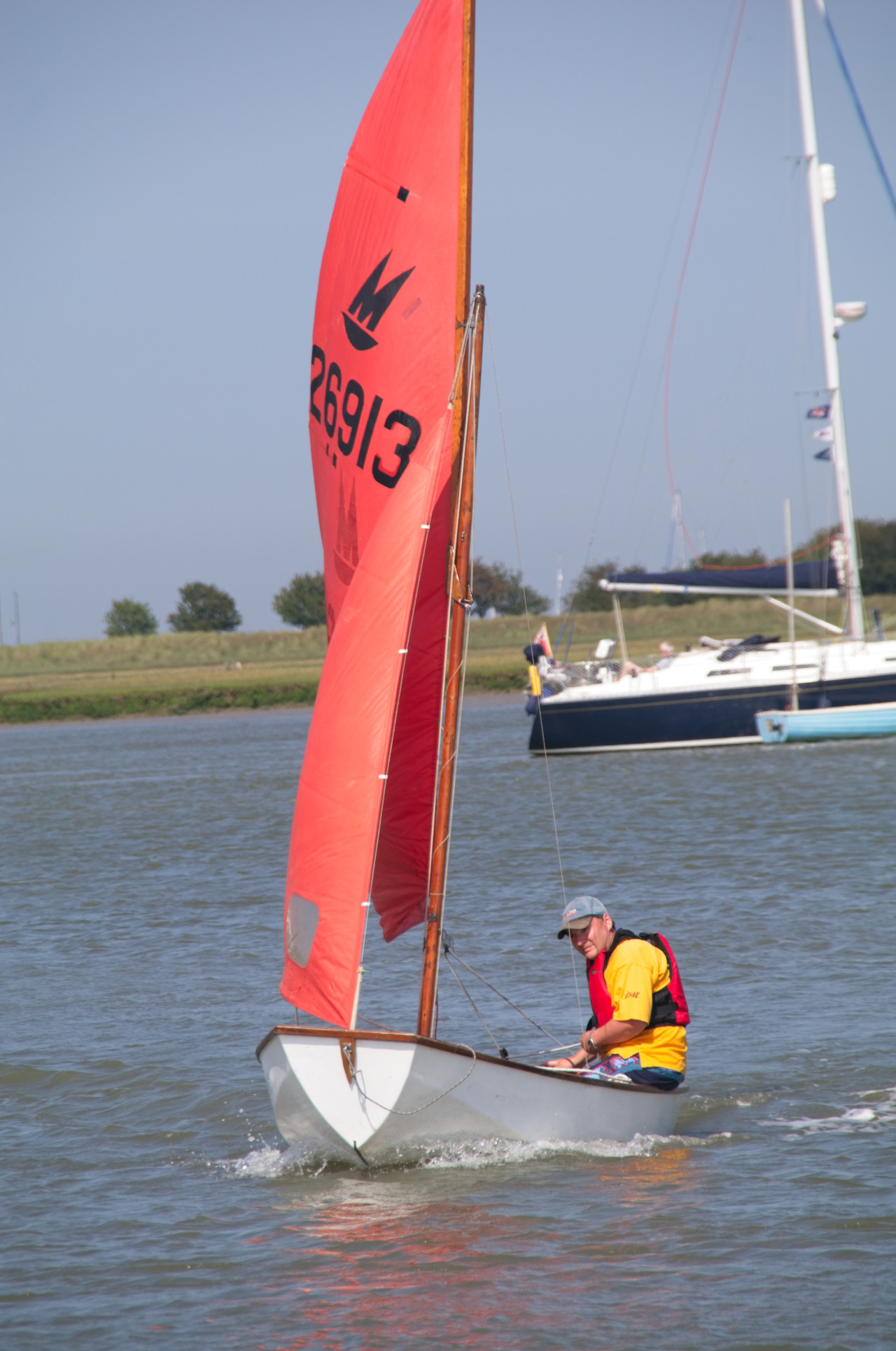 A Mirror dinghy being sailed singlehanded by a gentleman on a river