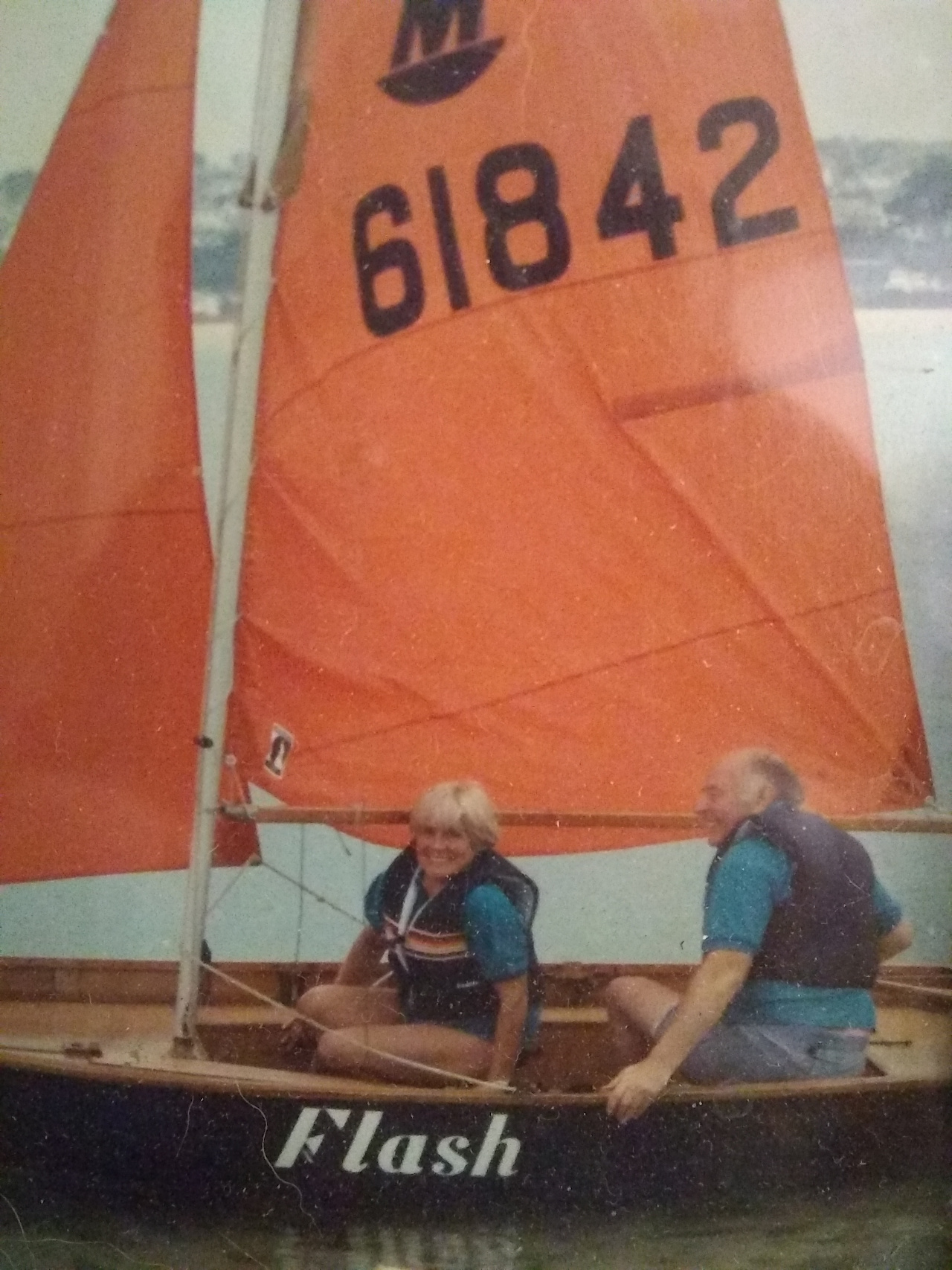 A Mirror dinghy being sailed by two adults in a harbour