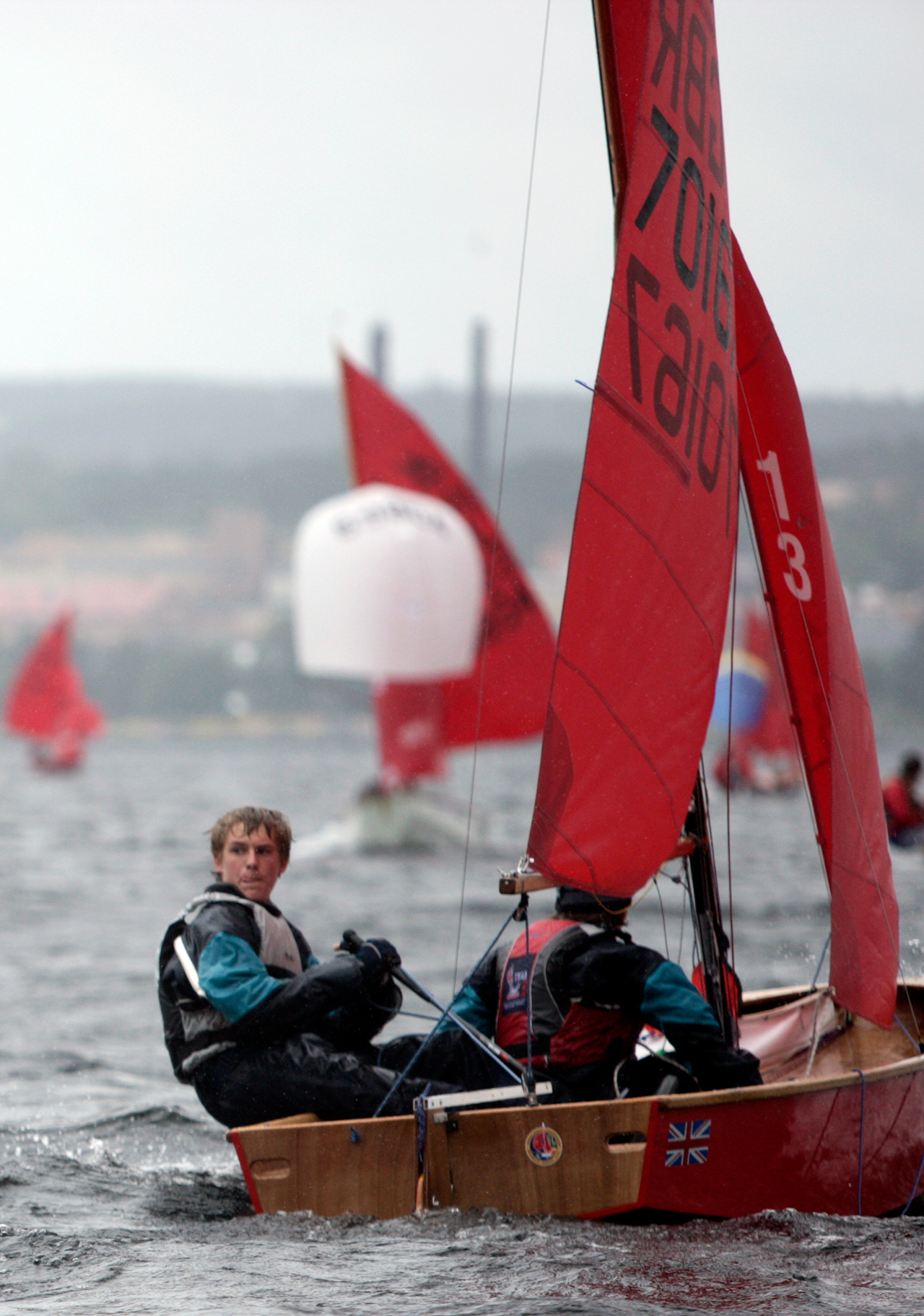 A red Mirror dinghy racing with helm looking to see if he can tack