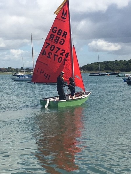 A green GRP Mirror dinghy being sailed