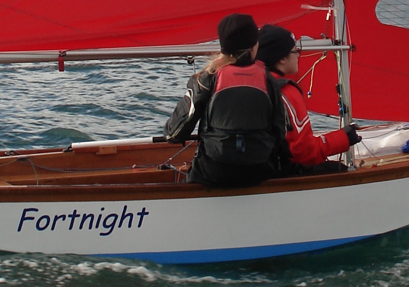 A Mirror dinghy sailing to windward with jib fairleads and cleats visible on the sidedeck