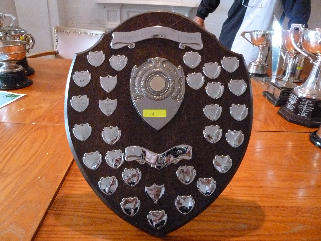 A wooden shield with small engraved shields mounted on it