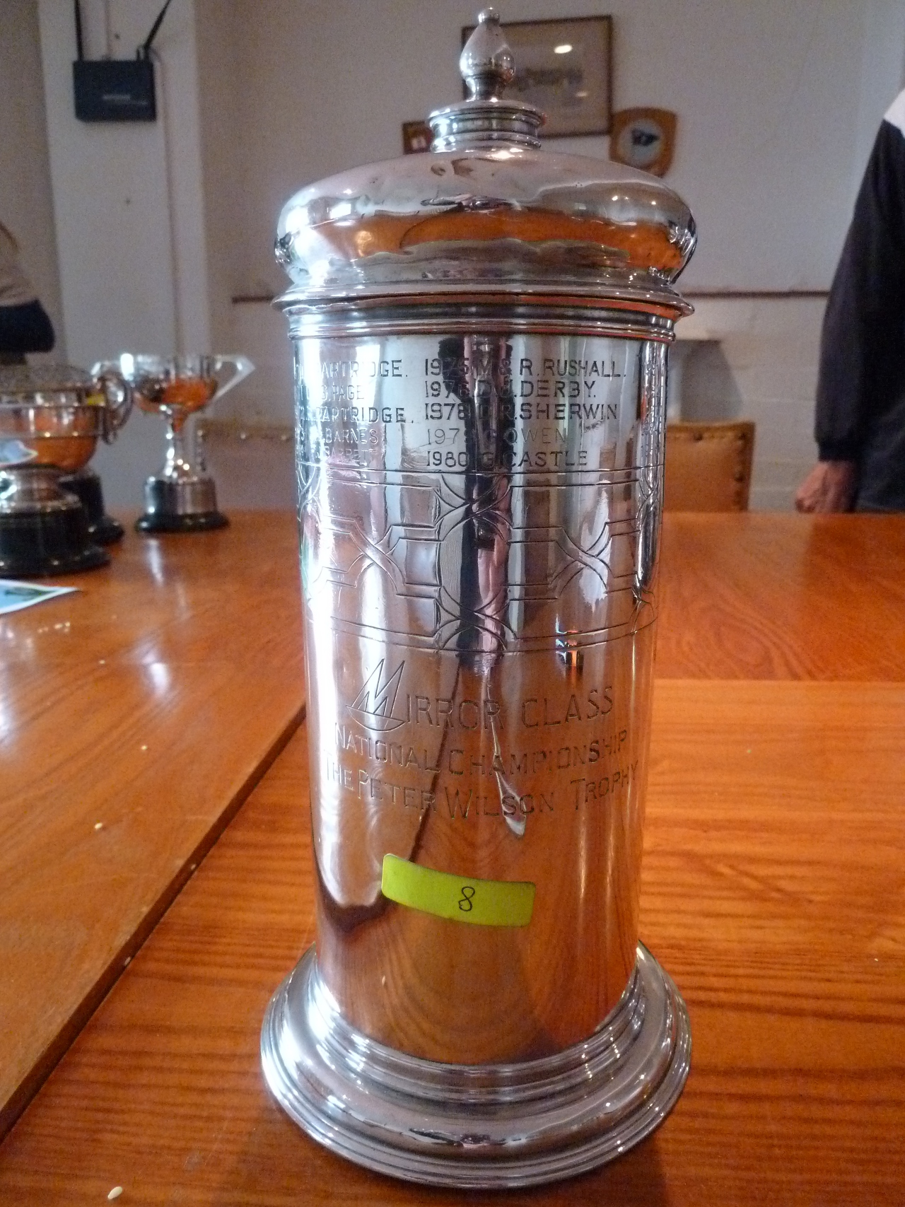A tall silver cup with a handle and a lid
